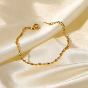 Bracelet chaîne à billes ovales en acier doré 18K sur fond élégant en soie de couleur beige