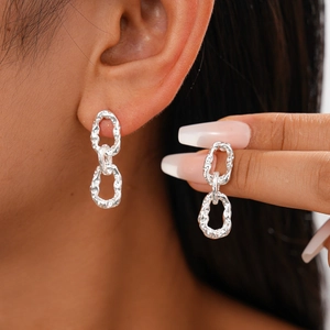 Boucles d'oreilles ovales argentées style chaîne portées par un mannequin chic