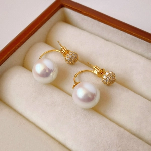 Macro shot of gold plated earrings with large white pearls and sparkling cubic zirconia