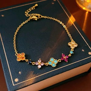 Detailed shot of gold bracelet featuring multicolored zirconia clovers on a vintage book