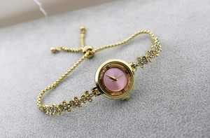 Close-up of pink dial watch with diamond accents and gold adjustable sliding chain strap