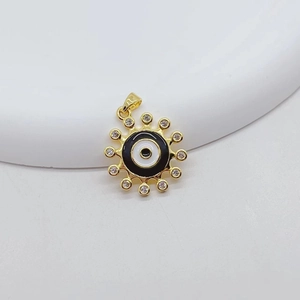 Macro view of gold Evil Eye pendant with white crystals and enamel sunburst details