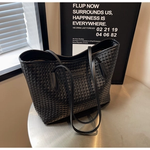 Detailed view of black woven tote bag with FASHION label on a metal table