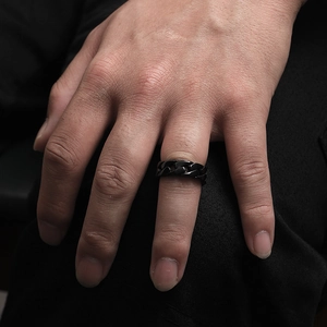 Macro detail of men's black stainless steel curb chain ring worn on finger