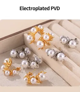 Detail view of gold and silver PVD plated earrings with three pearls in a jewelry box