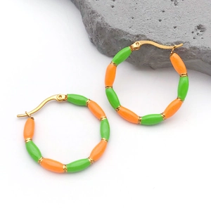 Detail view of gold-plated bamboo hoop earrings with vibrant orange and green enamel drip