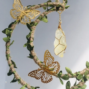 Detailed close-up of handmade moon wind chime with gold butterflies and crystal pendant