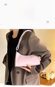 Detail shot of a pink patent leather baguette bag styled with a modern outfit