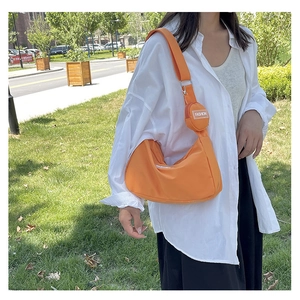 Detail of orange nylon crossbody bag with wide strap and matching round coin purse
