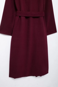 Détail de la texture du manteau en laine bordeaux et du design de la ceinture assortie