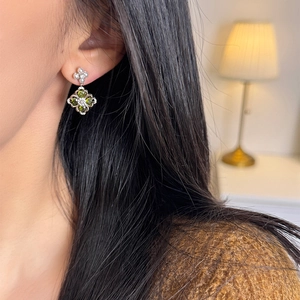 Close-up of sparkling flower earrings with green zircon and pearls on model ear