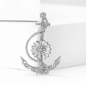 Macro shot of silver anchor brooch with sparkling rhinestones on a white geometric base