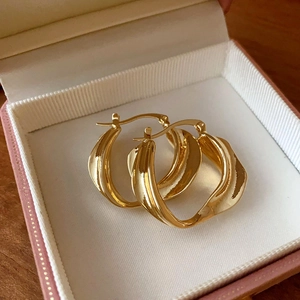 Exaggerated golden twisted hoop earrings with a geometric textured finish in a gift box