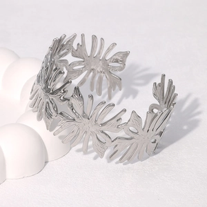Detailed view of silver hollowed flower open bangle on elegant white geometric pedestal