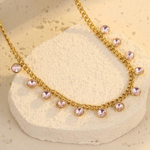 Detailed close-up of gold chain necklace featuring faceted pink gemstones on stone base