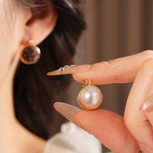 Close-up of leopard print and pearl earrings with golden frames on a model ear