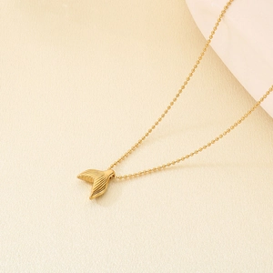 Detailed view of golden fish tail pendant with hammered texture on a chic bead chain