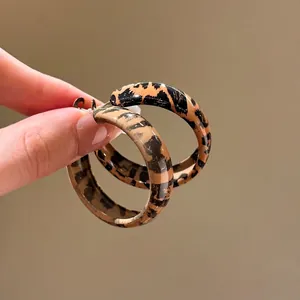 Retro leopard print resin hoop earrings for women shown held by hand for scale
