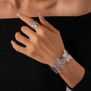 Detail of silver floral cuff bracelet and ring set with brushed metal texture