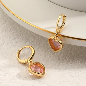 Détails de boucles d'oreilles cœur rose avec anneaux dorés sur décor élégant en céramique