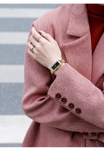 Elegant gold square watch with black dial and metal mesh strap on model's wrist