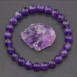 Detailed view of natural amethyst beaded bracelet with raw purple crystal on textured background