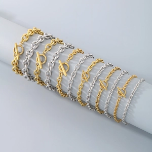 Close-up of gold and silver OT buckle chain bracelets on a grey display cylinder