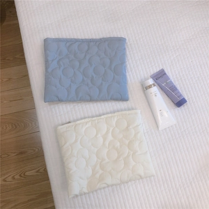 Detailed close-up of floral quilted down pouch in light blue and cream with zip top