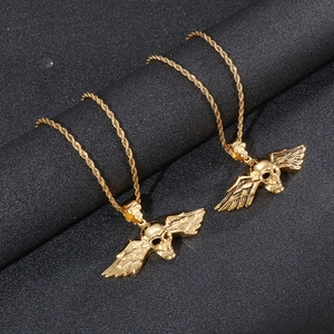 Détail de deux pendentifs tête de mort ailes d'ange dorés avec chaînes torsadées