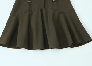 Détail d'une robe en sergé vert foncé avec ourlet à volants et boutons décoratifs dorés