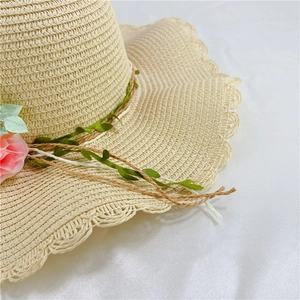 Detailed macro view of scalloped edge straw hat with pink floral accents and weave texture