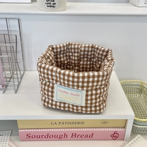 Detailed close-up of brown and white plaid quilted fabric storage basket on desk
