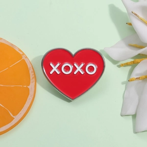 Épinglette cœur rouge émaillé avec lettrage XOXO blanc sur fond décoratif élégant