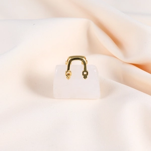 Detailed view of mini white crystal handbag pendant with gold handle on beige fabric
