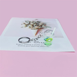 Detailed view of mini kiwi fruit tea cup keychain with faux green liquid and straw