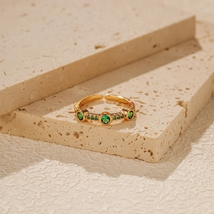 Macro shot of gold-plated open ring featuring three large green cubic zirconia stones