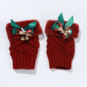 Detail of red knitted fingerless gloves with bow, golden bells and faux fur trim