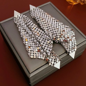 Detailed shot of silver mesh tassel earrings with triangular accents on a leather jewelry box
