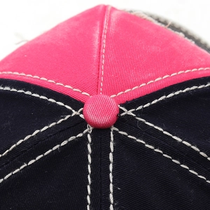 Macro detail of crown button and reinforced stitching on a washed cotton baseball cap