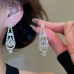 Detail shot of silver chandelier earrings featuring faceted crystals and pear-cut drops