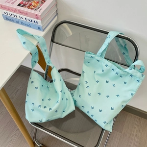 Mint green canvas tote bags featuring blue bird print displayed on a modern chair