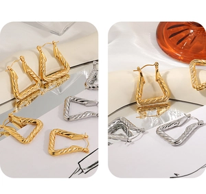 Detailed close-up of geometric triangle twisted hoop earrings in gold and silver finish