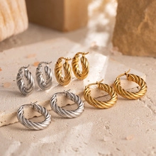 Collection of layered gold and silver twisted hoop earrings on natural stone surface