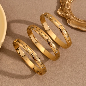Close-up of three 18K gold-plated star and eye bracelets with white rhinestones