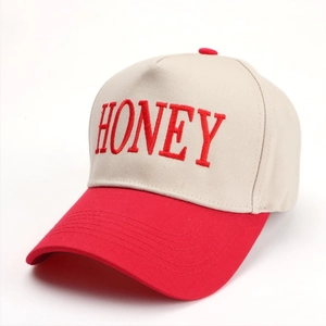 Close-up of HONEY letter embroidery on a beige and red color-block baseball cap