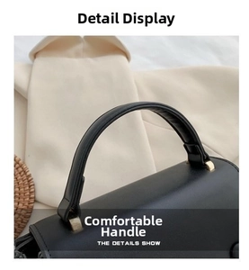 Detail of a black leather handbag featuring a reinforced handle and gold metal hardware