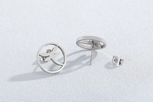 Macro view of stainless steel hollow circular earrings featuring a dragonfly design