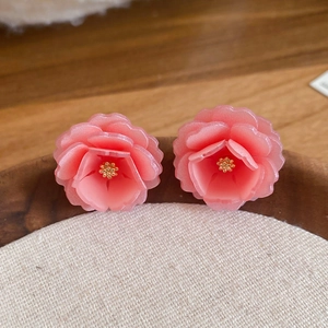 Vue macro de boucles d'oreilles fleurs en résine avec pétales rose dégradé