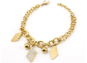 Dettaglio di un bracciale dorato a doppia catena con ciondoli geometrici e zirconi incastonati