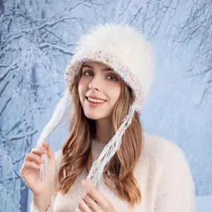 Winter white faux fur trapper hat with colorful knit trim and tassels on a model